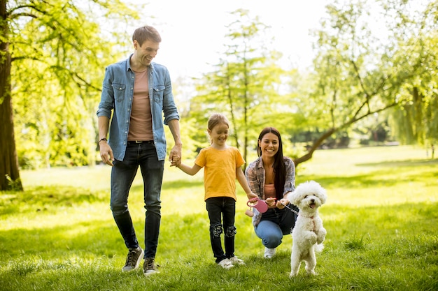 Schöne glückliche Familie hat Spaß mit maltesischem Hund im Freien