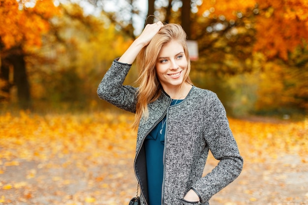 Schöne glückliche Frau im Herbst stilvolle Kleidung, die das Wetter nahe dem gelben Laub genießt