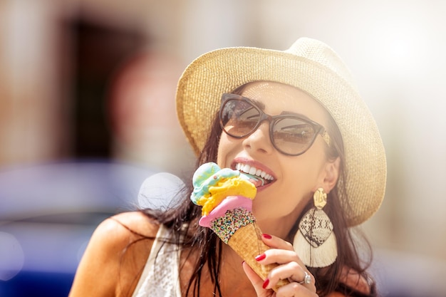 Schöne glückliche Frau leckt Eis an einem heißen Sommertag
