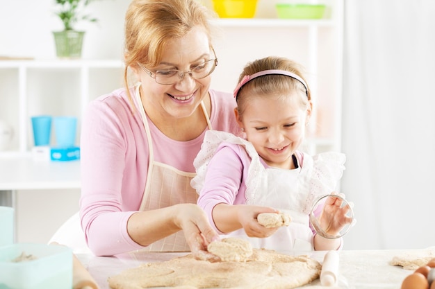 Schöne glückliche Großmutter und Enkelin backen in der Küche.