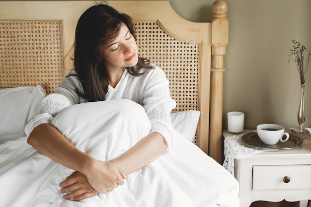 Schöne, glückliche junge Frau, die morgens im Hotelzimmer oder Schlafzimmer zu Hause im Bett liegt