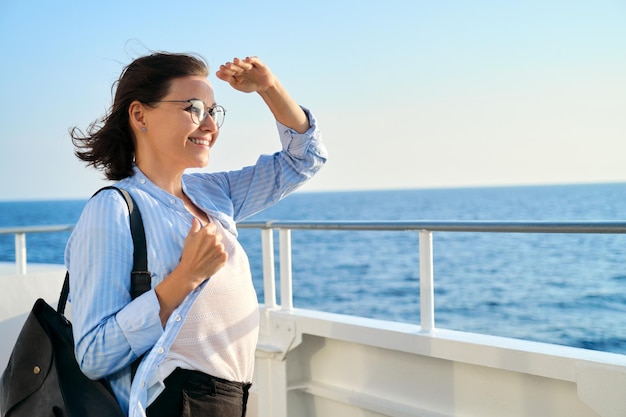 Schöne, glückliche, reife Frau auf Deck des Schiffes, Fähre, Seereise genießend, blauer Himmel, Sonnenuntergang, Kopienraum. Seeverkehr, Personenverkehr, Tourismus