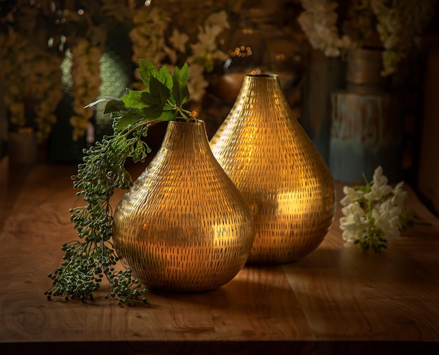 Schöne goldene Vasen mit künstlichen Blumen auf einem Holztisch Haushaltsgegenstände retro