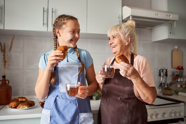 Schöne Großmutter, die zusammen mit ihrer Enkelin Gebäck probiert?