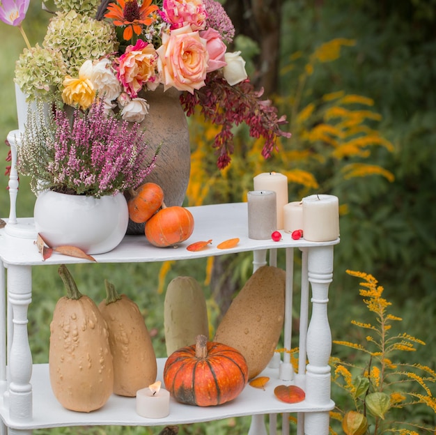 Schöne Herbstdekoration mit Blumen, Beeren, Kürbissen im Garten