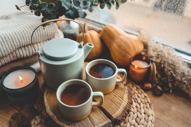 Schöne Herbstkomposition mit brennenden Kerzen und einer Tasse Tee auf der Fensterbank