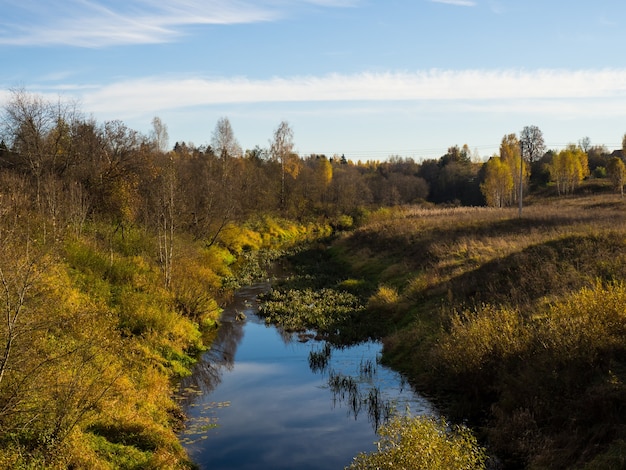 Schöne Herbstlandschaft mit einem Fluss an einem sonnigen Tag