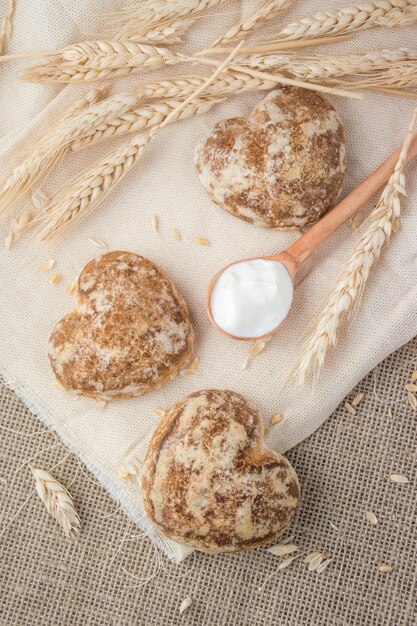 Schöne herzförmige Lebkuchenplätzchen sind mit Sauerrahm arrangiert Köstliche Kekse mit Ährchen