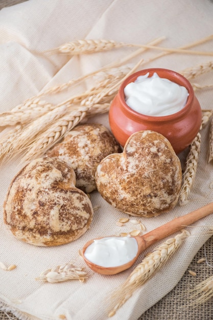 Schöne herzförmige Lebkuchenplätzchen werden mit Sauerrahm arrangiert Köstliche Kekse