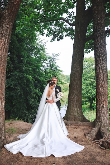 Schöne Hochzeitspaare im Park. Braut und Bräutigam umarmen sich im Freien