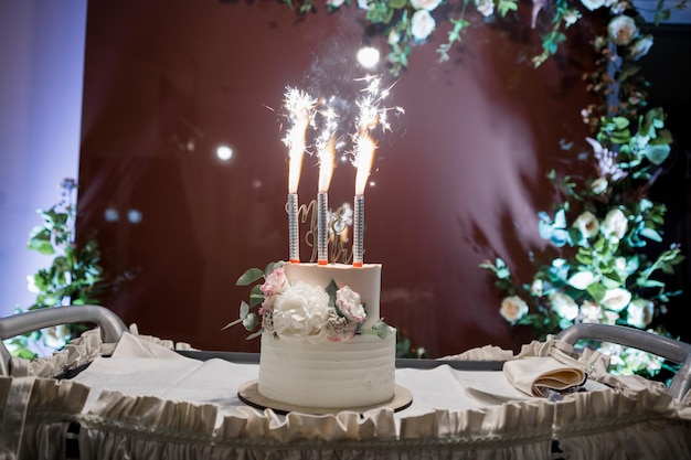 Schöne Hochzeitstorte auf einem Tisch mit Lichtern