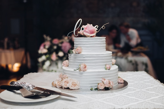 Schöne Hochzeitstorte mit Blumen auf Tabelle