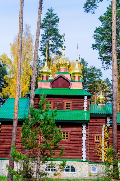 Schöne Holzkirche mitten in einem herbstlichen Wald mit Holzbrücke