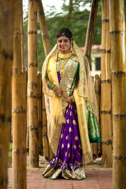 Schöne indische Braut in traditioneller Saree posiert im Freien im Park