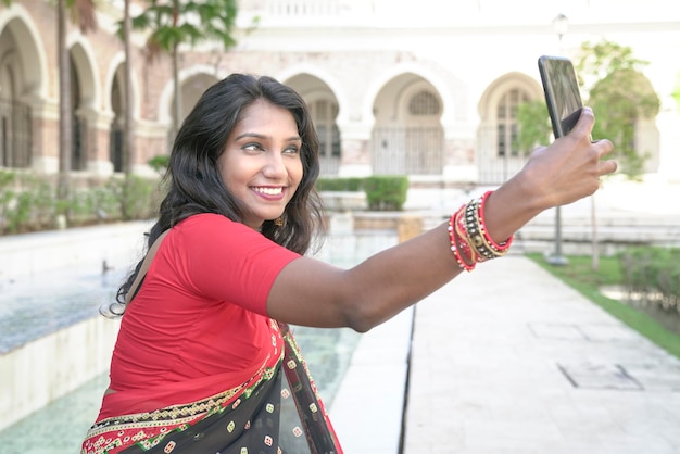 Schöne indische Frau mit Kameratelefon, um ein Selbstporträt zu machen