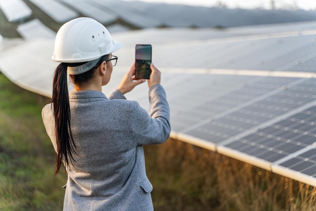 Schöne Ingenieurin, die Handy hält, während sie in der Nähe des Solarpanels steht