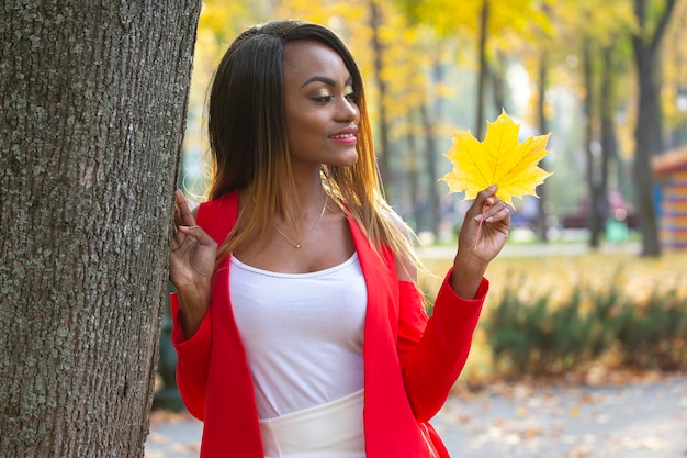 Schöne junge afrikanische Frau mit Herbstblatt in ihren Händen