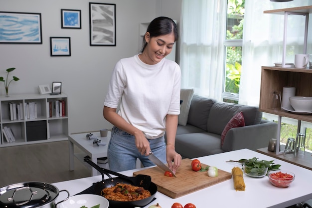 Schöne junge asiatische Frau bereitet Essen in der Küche zu Hausfrau, die zu Hause in der Küche kocht