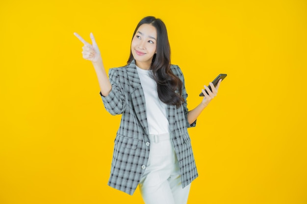Schöne junge asiatische Frau des Porträts lächeln mit intelligentem Handy auf Farbhintergrund