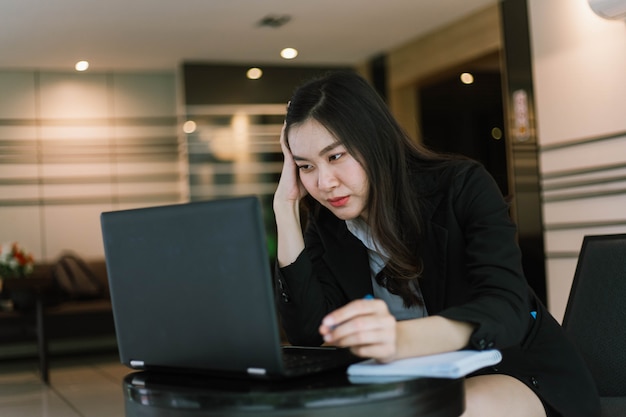 Schöne junge asiatische Frau, die ihren Laptop benutzt