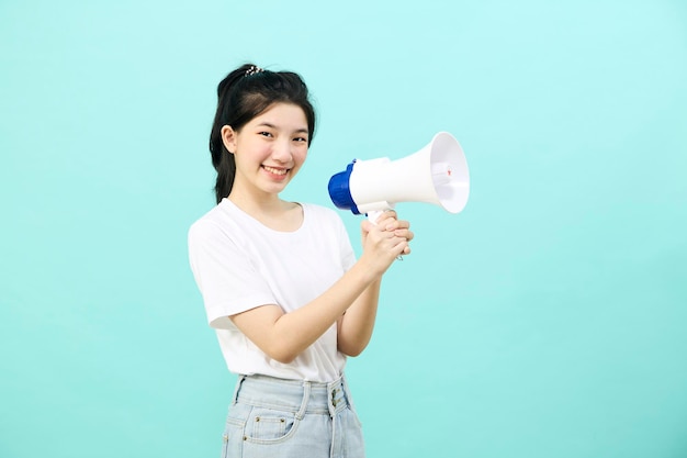 Schöne junge asiatische Frau, die Megaphon auf blauem Hintergrundstudio hält