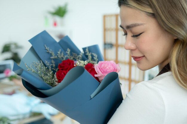 Schöne junge asiatische Frau hält einen Blumenstrauß im Blumenladen