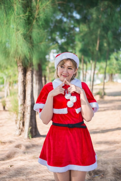 Schöne junge asiatische Frau in Weihnachtsmann-Kleidung im Freien