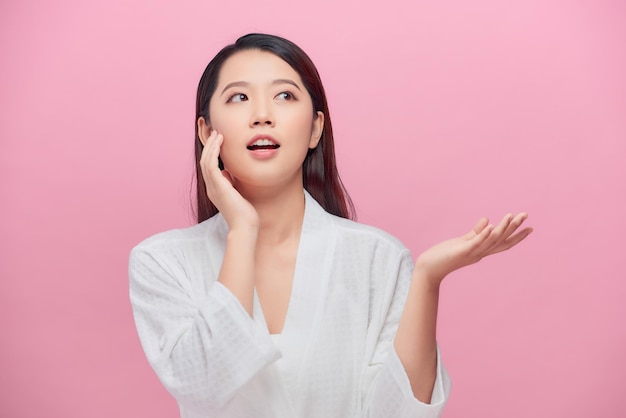 Schöne junge asiatische Frau mit sauberer frischer weißer Haut, die ihr eigenes Gesicht sanft in Schönheitshaltung berührt.