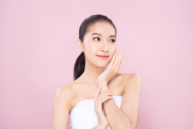Schöne junge asiatische Frau mit sauberer frischer weißer Haut, die ihr eigenes Gesicht sanft in Schönheitspose berührt.