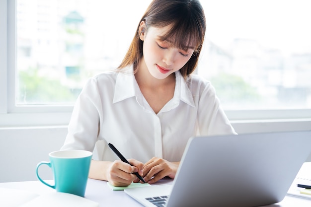 Schöne junge asiatische Geschäftsfrau arbeitet online mit guter Laune