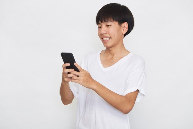 Schöne junge asiatische Mann Student SMS-Nachrichten mit Smartphone auf einer hellen Oberfläche. Kopieren Sie Speicherplatz und Modell