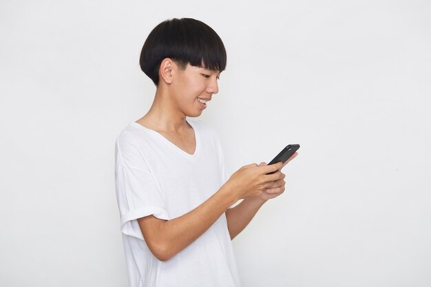 Schöne junge asiatische Mann Student SMS-Nachrichten mit Smartphone auf einer hellen Oberfläche. Kopieren Sie Speicherplatz und Modell
