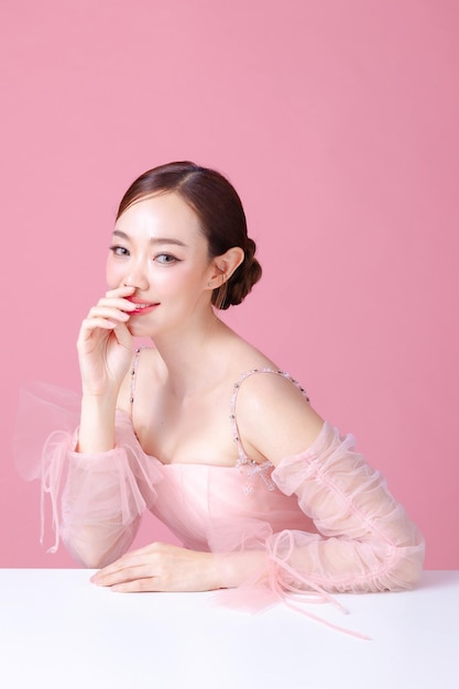 Foto schöne junge asiatische modelfrau mit bunnen haaren mit natürlichem make-up auf dem gesicht saubere frische haut auf isoliertem rosa hintergrund süßes mädchen porträt gesichtsbehandlung valentinstagskonzept