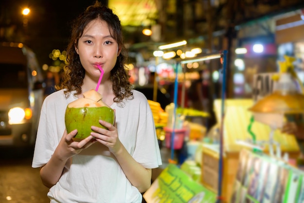 Schöne junge asiatische Touristenfrau im Urlaub Sightseeing und Erkunden an der Khao San Road in der Nacht in der Stadt Bangkok Thailand Urlaub und Reisekonzept