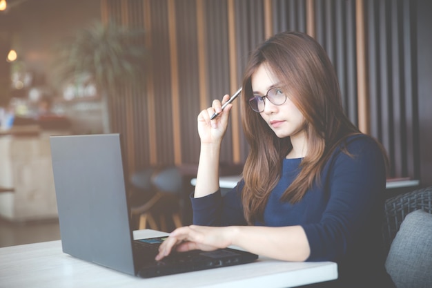 Schöne junge Asienfrau, die mit Computer arbeitet