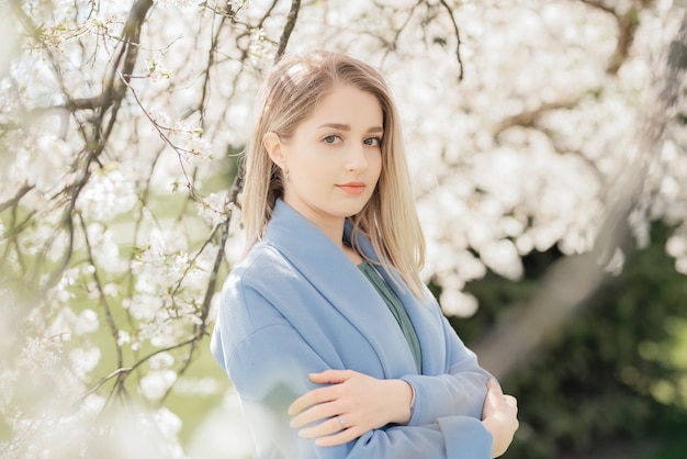 Schöne junge blonde Frau, die nahe dem Apfelbaum steht