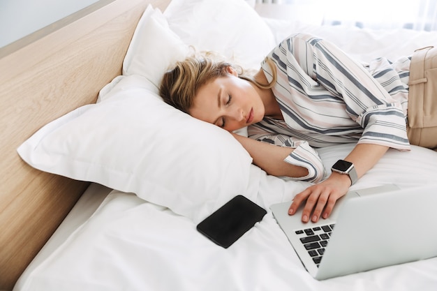 Schöne junge blonde Frau, die sich zu Hause im Bett entspannt