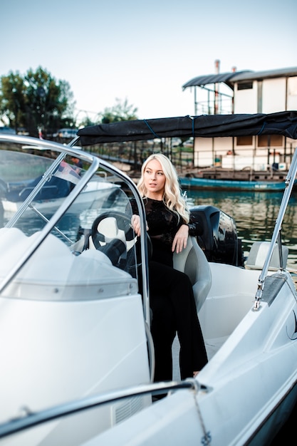 Schöne junge blonde Frau, ein Boot auf dem Wasser reitend.