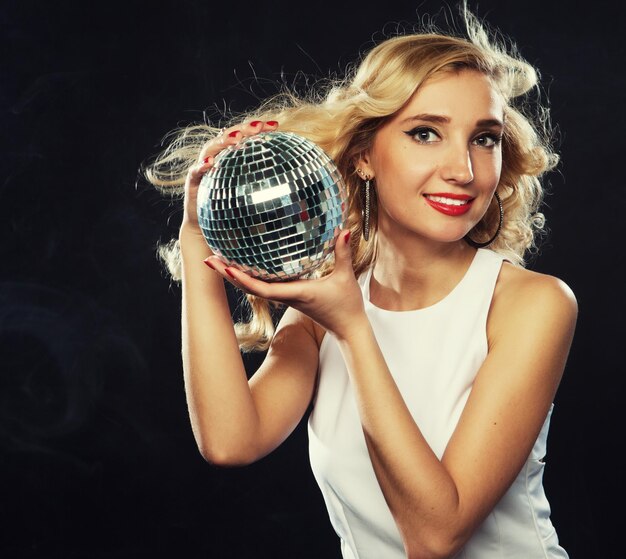 Schöne junge blonde Frau mit Discokugel im Nachtclub