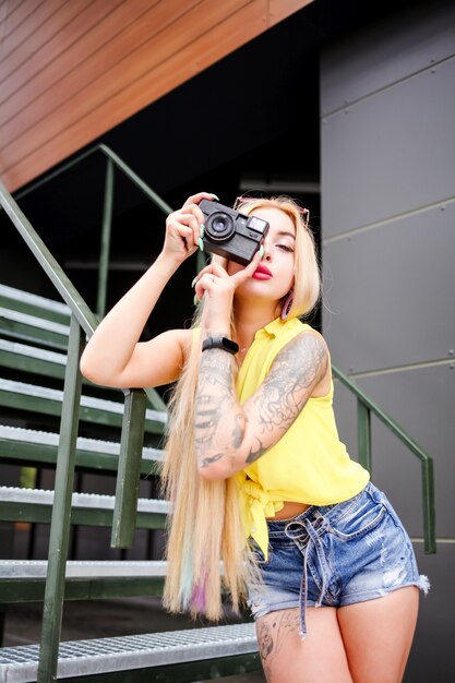 Schöne junge blonde Frau mit einer Kamera in ihren Händen
