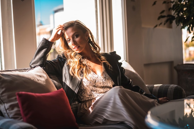 Schöne junge blonde kaukasische Frau auf dem Sofa des Hotels, in dem sie im Urlaub ist