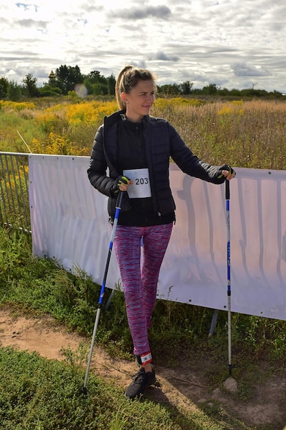 Schöne junge blonde Nordic-Walking-Athletin posiert nach dem Wettkampf und lächelt