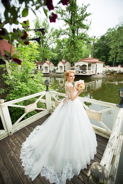 schöne junge Braut in einem sanften Hochzeitskleid für einen Spaziergang in einem Sommerpark