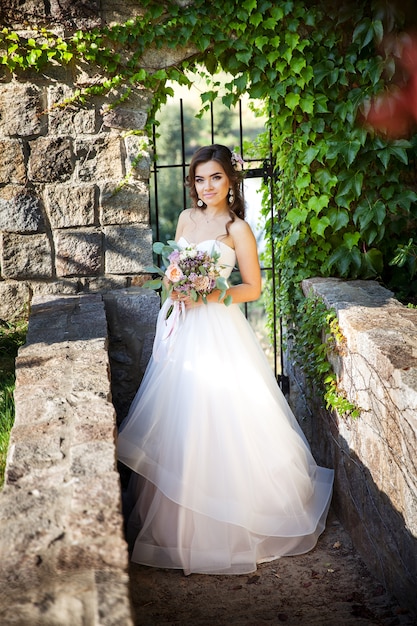 Schöne junge Braut mit einem Blumenstrauß der Hochzeitsblumen. Urlaubskleid