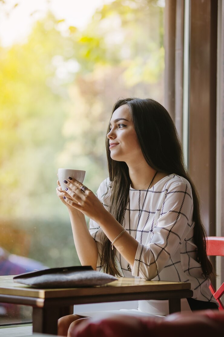 Schöne junge Brünette, die in einem Café sitzt und Tee trinkt.