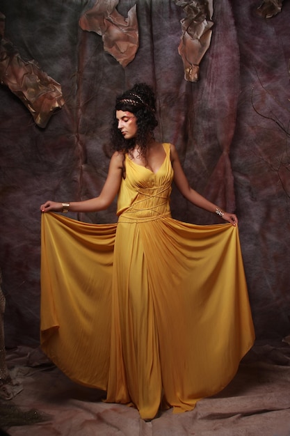 Schöne junge Brünette Frau, die gelbes Abendkleid trägt