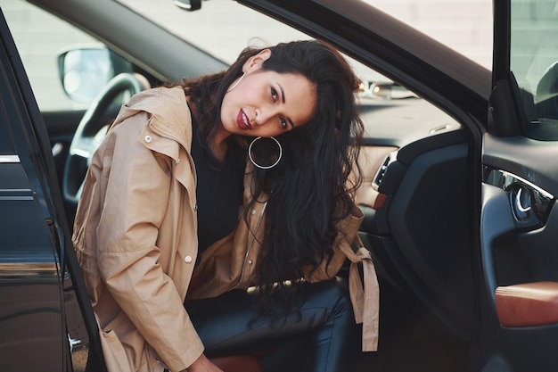 Foto schöne junge brünette mit lockigem haar, die in einem modernen auto sitzt