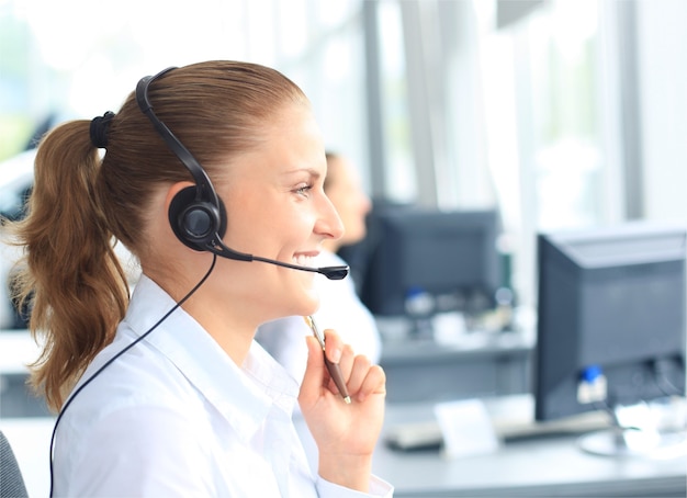 Schöne junge Callcenter-Betreiberin mit Headset im Büro