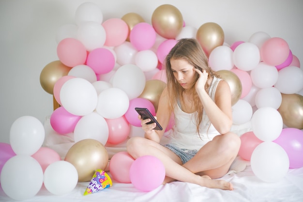 Schöne junge Dame, die auf Smartphone in ihrem Schlafzimmer tippt.