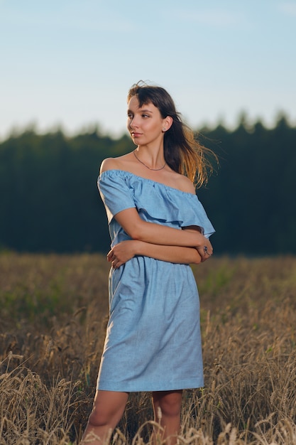 Schöne junge Dame im Weizenfeld bei Sonnenuntergang